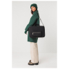 Model draagt de zwarte SKFK Cistella tas, draagbaar als crossbody, schoudertas of rugzak, gemaakt van 70% gerecycled polyester, duurzaam en fair geproduceerd.